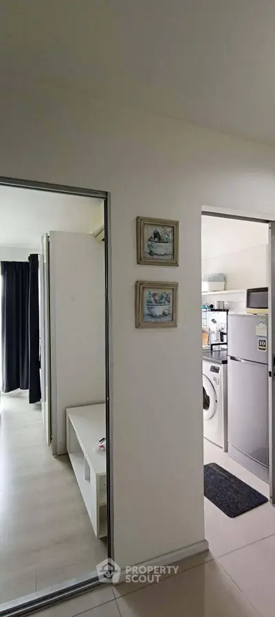 Modern apartment interior with washing machine and fridge in compact kitchen area.