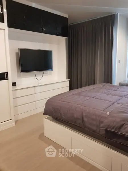 Modern bedroom with sleek design, featuring a wall-mounted TV and stylish storage solutions.