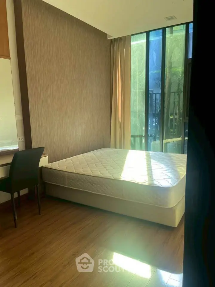 Bright bedroom with large window and wooden flooring, perfect for natural light lovers.