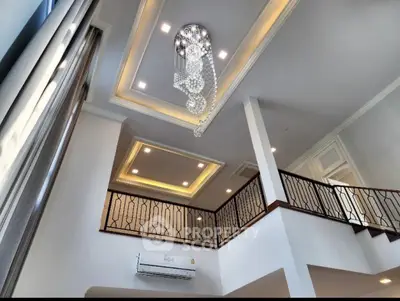 Luxurious high-ceiling living room with elegant chandelier and modern design.