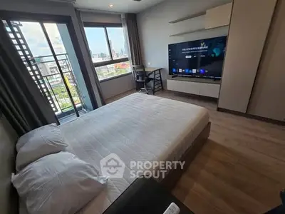 Modern bedroom with large window and city view, featuring a sleek TV and minimalist decor.