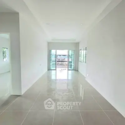 Spacious empty living room with large windows and balcony access, perfect for customization.