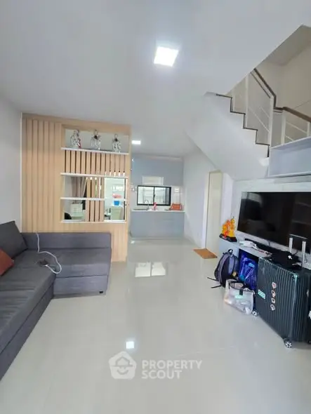 Spacious modern living room with sleek design and staircase, perfect for family gatherings.