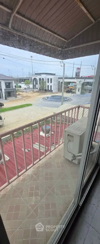 Spacious balcony with scenic view of modern residential complex entrance.