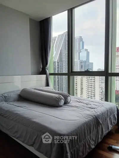 Modern bedroom with floor-to-ceiling windows offering stunning city views in a high-rise apartment.