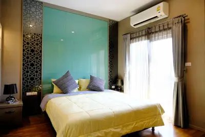 Modern bedroom with stylish decor and natural light, featuring a comfortable bed and elegant curtains.