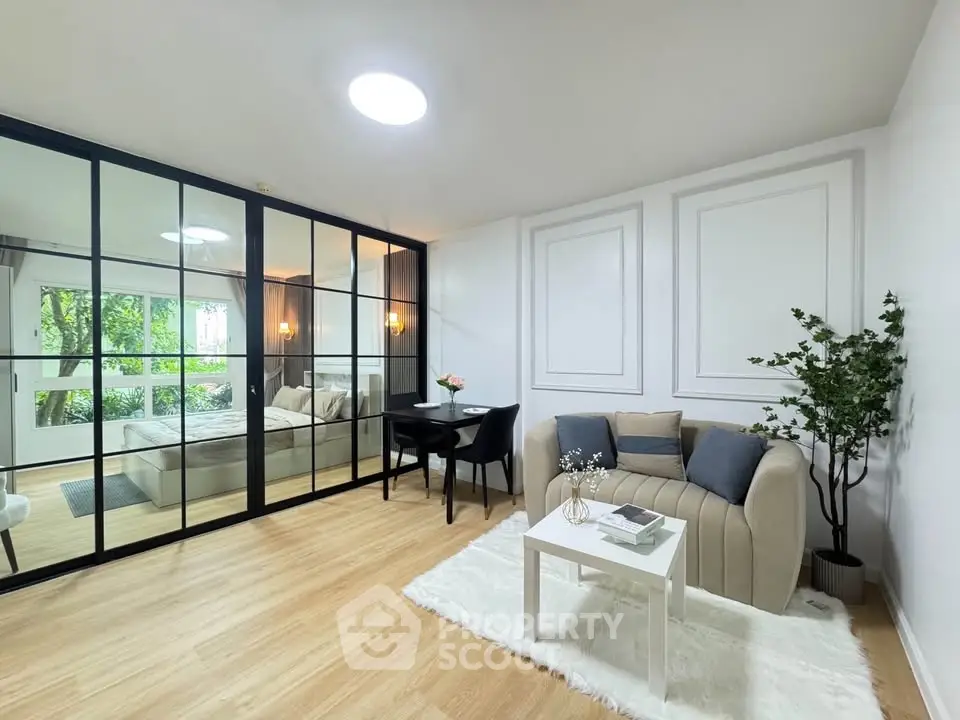 Modern living room with glass partition, cozy seating, and elegant decor