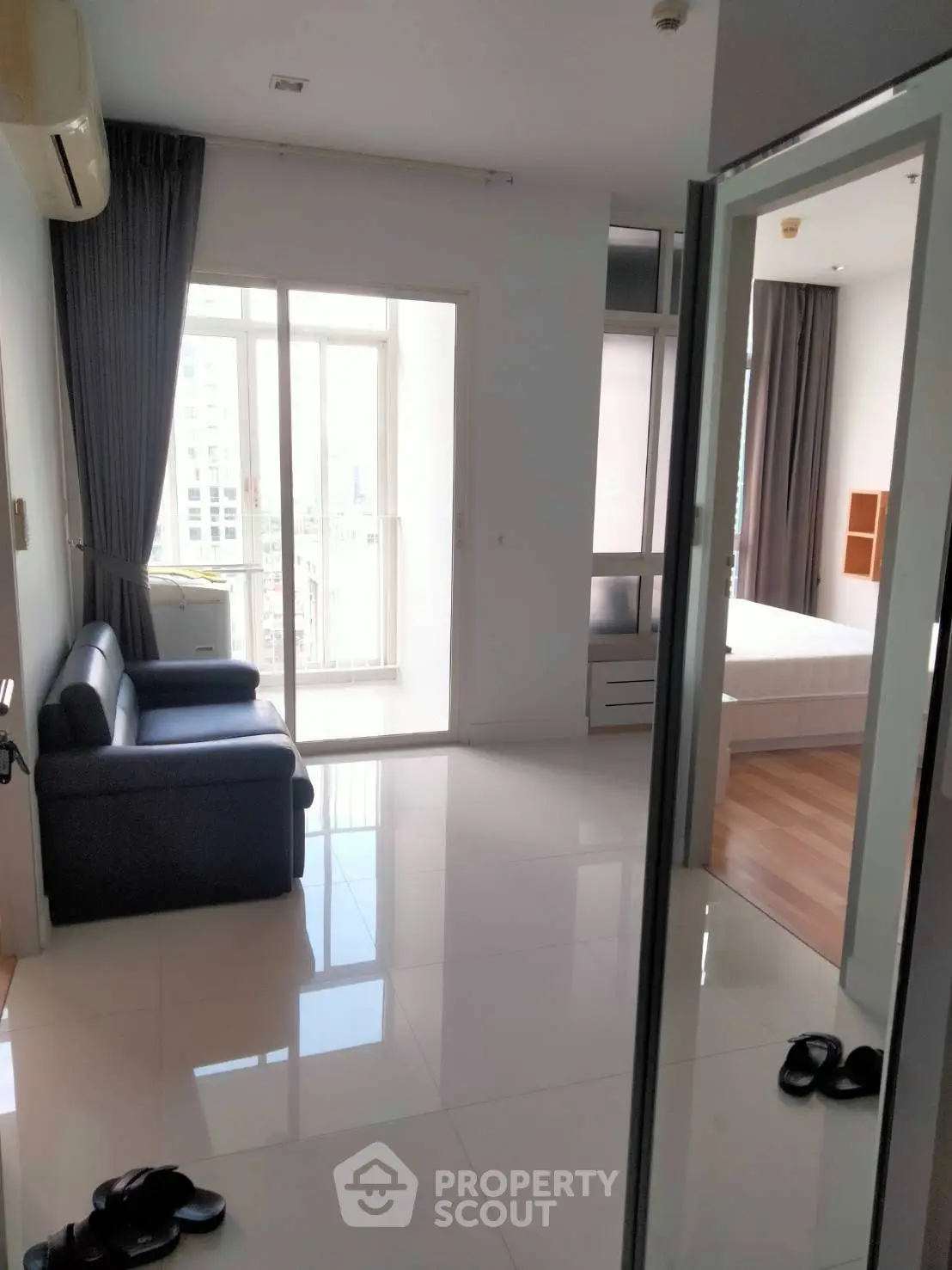 Modern apartment interior with sleek living room and bedroom, featuring large windows and glossy flooring.
