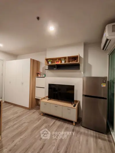 Modern living room with sleek furniture and stainless steel fridge, perfect for contemporary living.