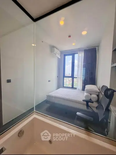 Modern bedroom with glass wall overlooking bathtub and city view, featuring sleek design and natural light.