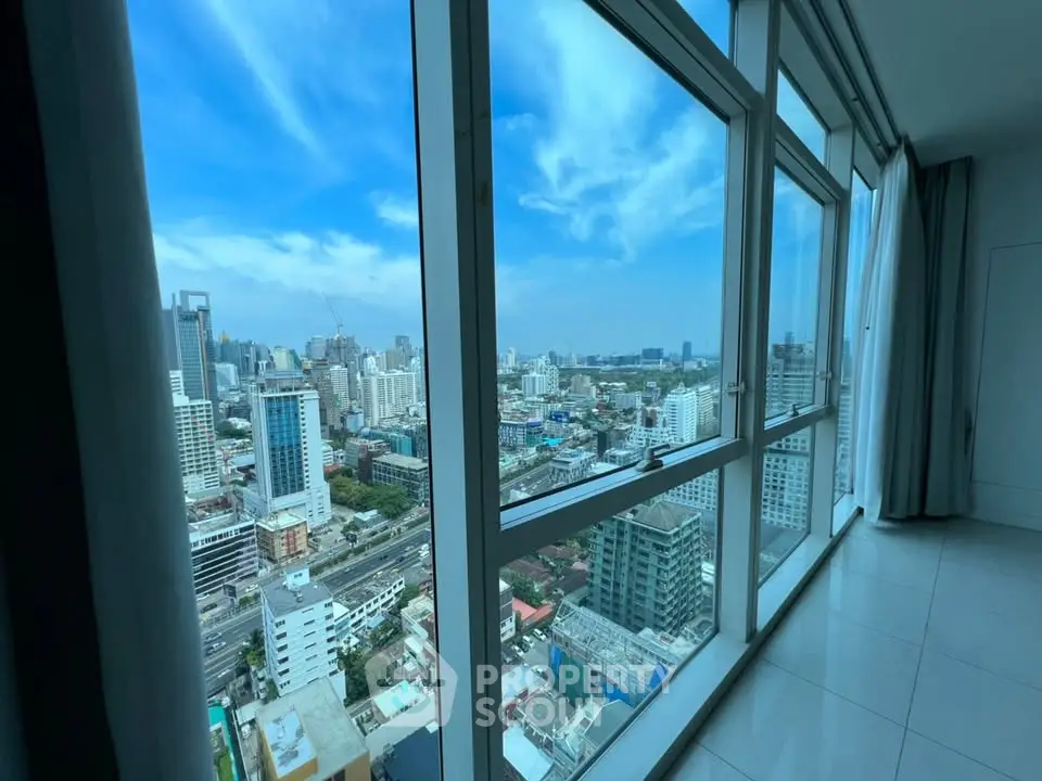 Stunning cityscape view from high-rise apartment with floor-to-ceiling windows.