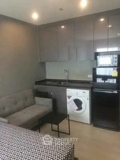 Modern studio apartment with compact kitchen and cozy living area, featuring washing machine and sleek appliances.
