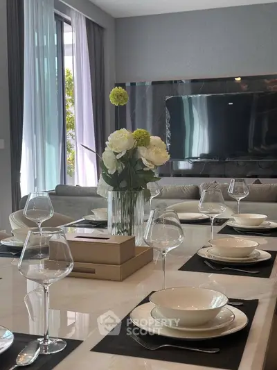 Elegant dining area with modern table setting and large TV in luxury living room.