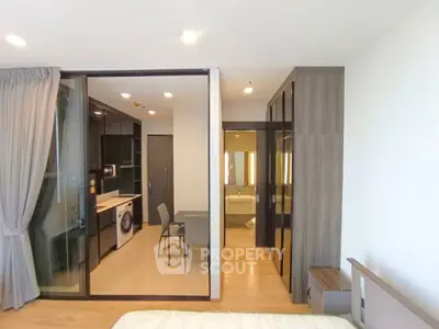 Modern apartment interior with open kitchen and bedroom, featuring sleek design and integrated appliances.