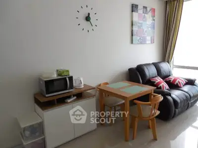 Cozy living room with modern decor, featuring a leather sofa, dining table, and wall clock.