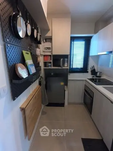 Modern kitchen with sleek cabinetry and wall-mounted cookware, featuring an oven and compact layout.