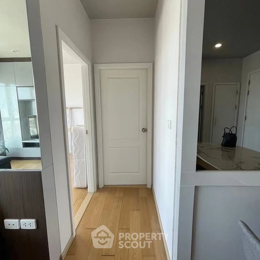 Modern apartment hallway with wooden flooring and white doors