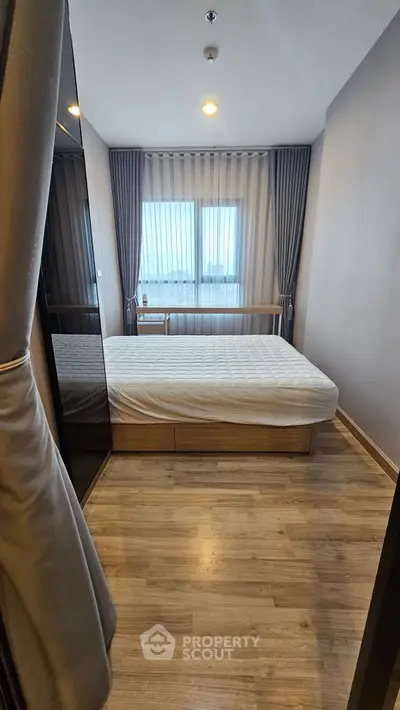 Modern bedroom with sleek design, featuring a comfortable bed and large window with elegant curtains.