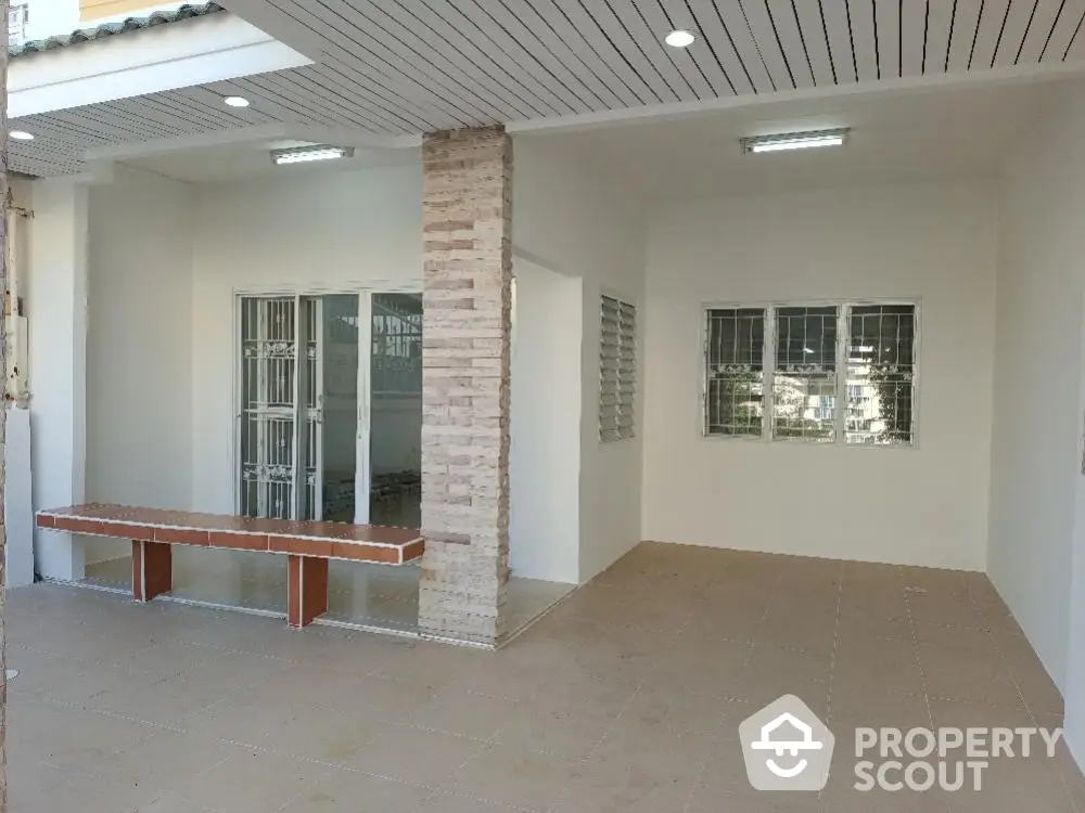 Spacious and modern open-plan living area with sleek tiling, abundant natural light from large windows, and a unique central brick feature column.