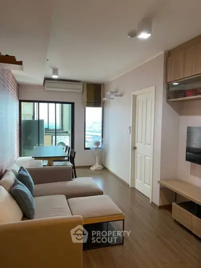 Modern living room with cozy seating and balcony view in stylish apartment.