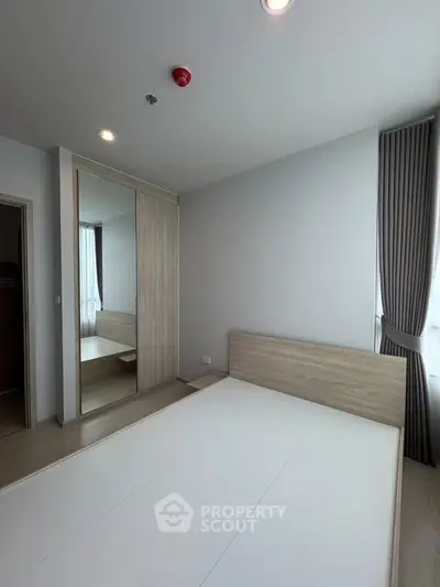 Modern minimalist bedroom with large mirror wardrobe and natural light