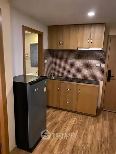 Compact kitchen with wooden cabinets and modern appliances in cozy apartment