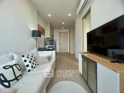 Modern living room with stylish decor and open kitchen layout, featuring a cozy sofa and large TV.