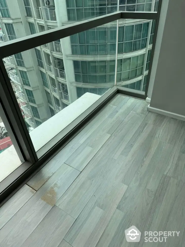 Modern apartment with floor-to-ceiling windows and city view, featuring sleek wooden flooring.