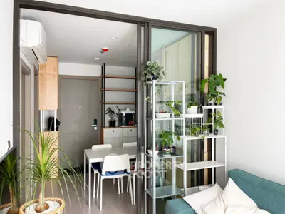 Modern living room with glass partition, indoor plants, and stylish furniture