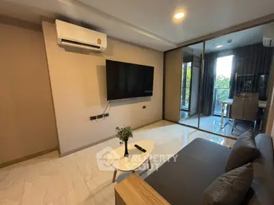 Modern living room with sleek design, featuring a wall-mounted TV and air conditioning, leading to a bright balcony.