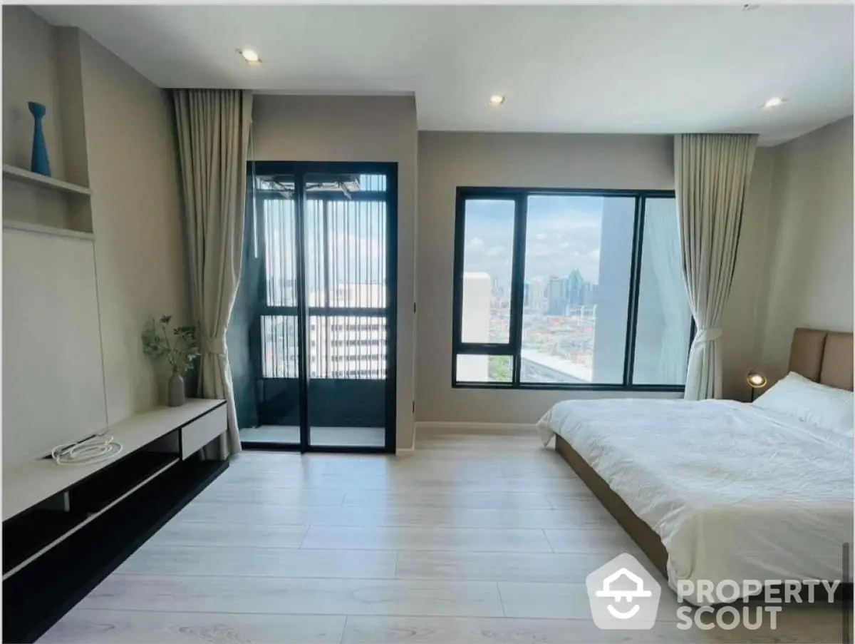 Spacious bedroom with city view and balcony access in modern apartment