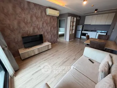 Modern living room with open kitchen, featuring stylish decor and natural light.