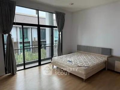 Spacious bedroom with large windows and balcony access in modern apartment.