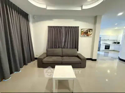 Spacious living room with modern sofa and open kitchen layout in a stylish home.