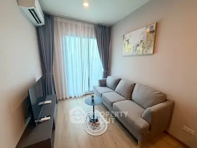 Modern living room with cozy gray sofa, stylish decor, and natural light from large window.