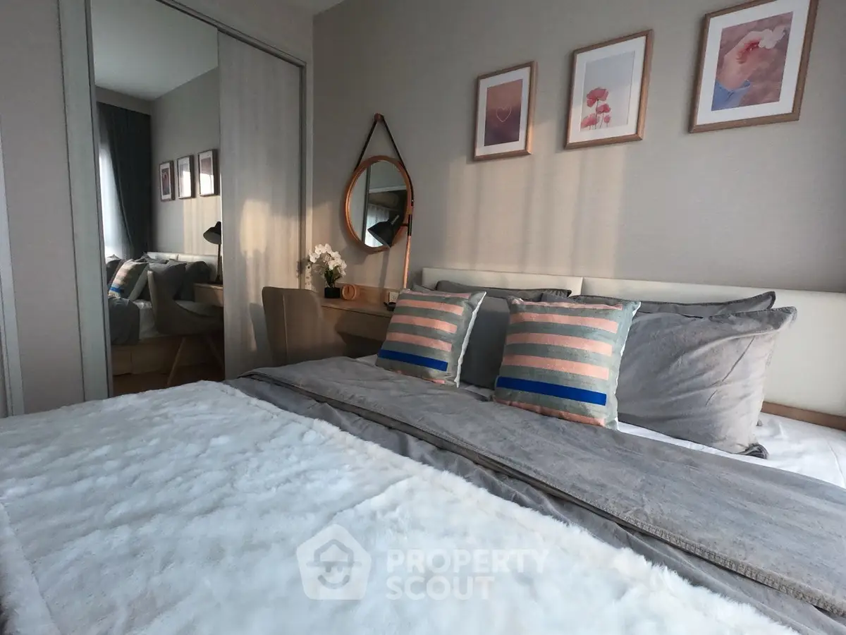 Cozy bedroom with stylish decor and plush bedding, featuring a mirror and framed art on the wall.