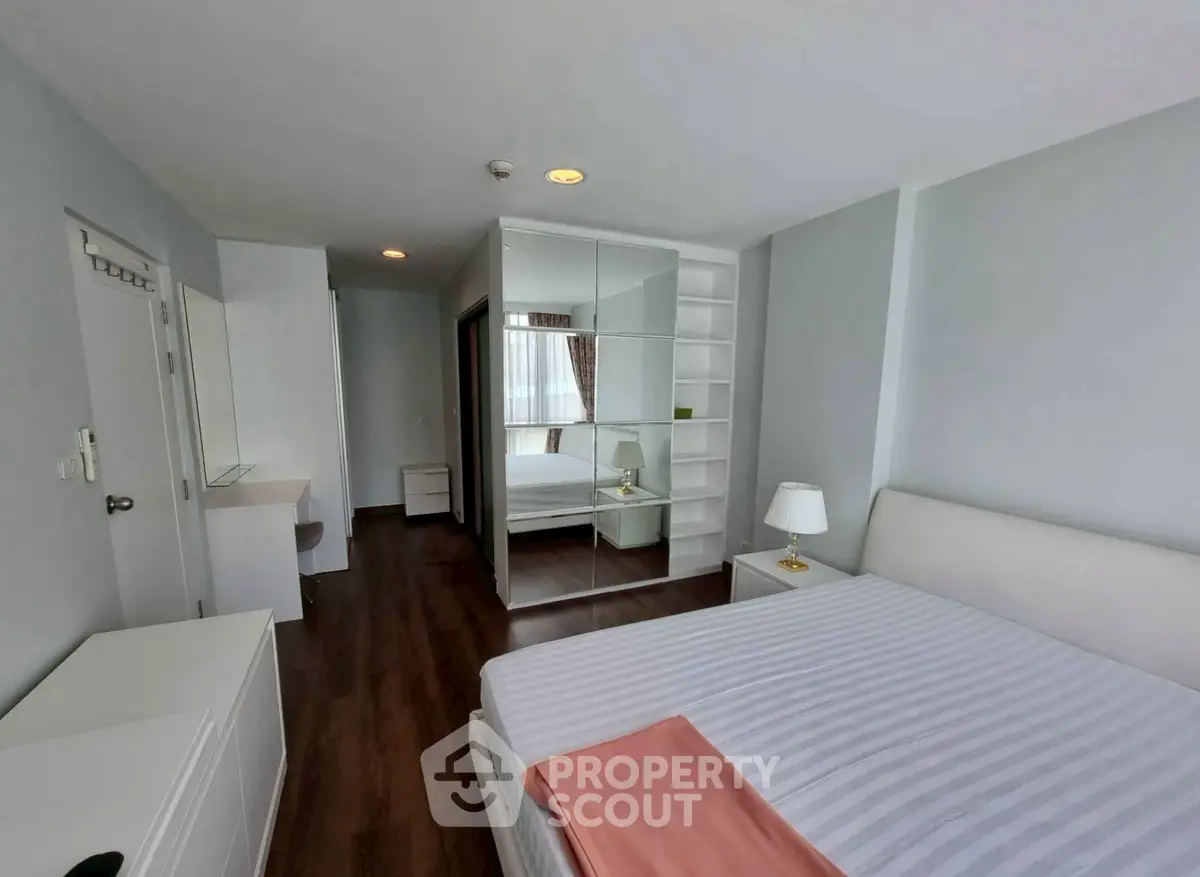 Spacious modern bedroom with mirrored wardrobe and elegant decor