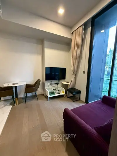 Modern living room with stylish furniture and large window offering city views.