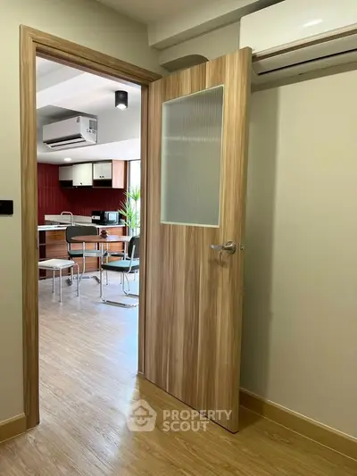 Modern kitchen with open layout and wooden flooring, featuring air conditioning and dining area.
