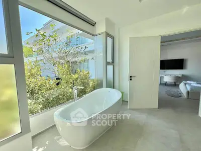 Luxurious bathroom with freestanding bathtub and garden view in modern home.