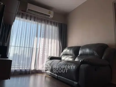 Cozy living room with leather sofa and large window offering natural light.
