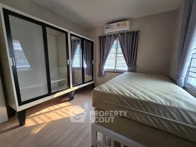 Spacious bedroom with large windows and modern wardrobe, perfect for comfortable living.