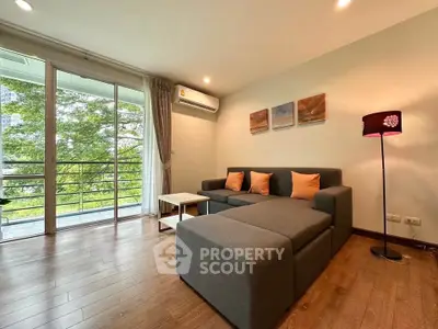 Spacious living room with modern sofa and balcony view, perfect for relaxation and entertaining.