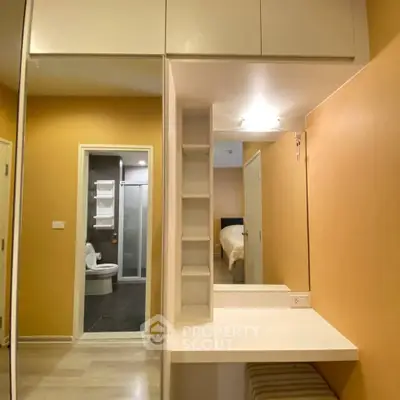 Modern apartment interior with bedroom and bathroom view, featuring sleek design and warm tones.