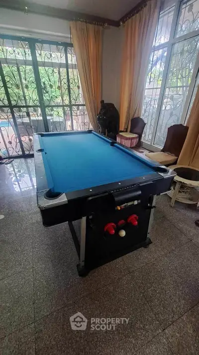 Spacious living room with pool table and large windows for natural light.