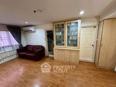 Spacious living room with wooden flooring and built-in storage cabinets.