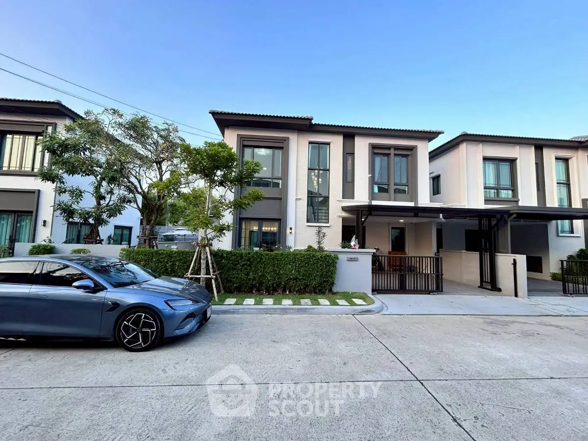 Modern two-story house with sleek design and manicured lawn in a suburban neighborhood.
