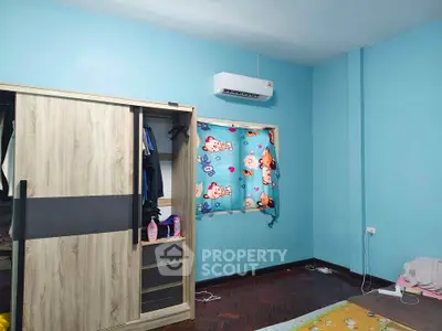 Cozy bedroom with blue walls, air conditioning, and wooden wardrobe, perfect for comfortable living.