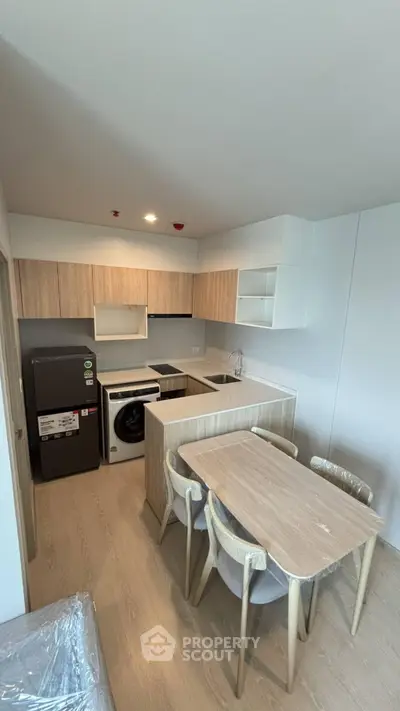 Modern kitchen with dining area, featuring sleek appliances and contemporary wooden cabinetry.