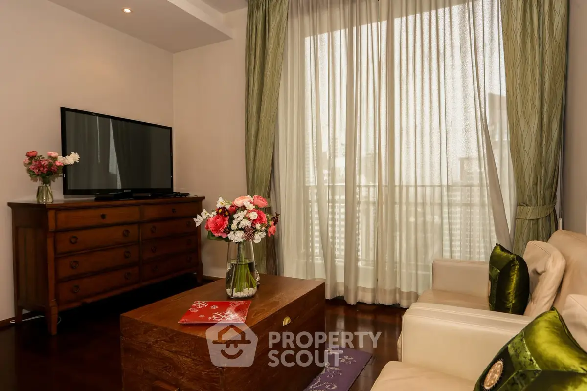 Elegant living room with large window, wooden furniture, and floral decor